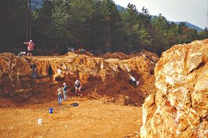 large pit in the ground with people digging inside and around it