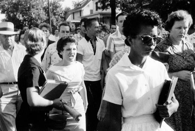 Black woman holding books with white woman screaming angrily at the black woman