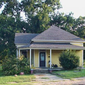 House with yellow paint and covered porch on street corner