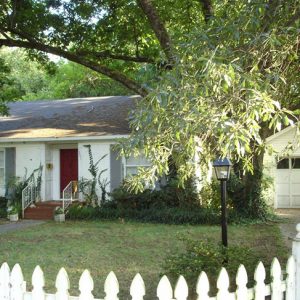 Single-story house with red door and garage with tree