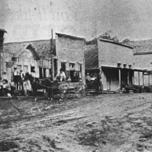 street scene with various storefronts and horse-drawn carts