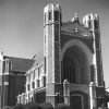 Brick church with large arch and stained glass window and twin towers