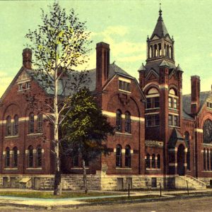 Multistory brick church building with stained glass windows and central tower with cupola on top