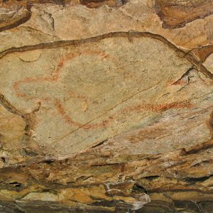 Faded red cave painting on rock wall