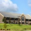 Two-story building with arched windows and prominent inset cross on hill