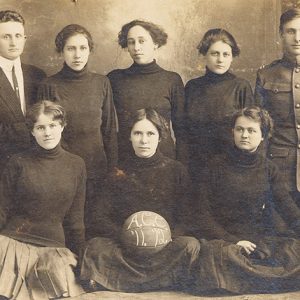 Young white women in matching skirts and turtleneck sweaters white man in suit and white man in military uniform