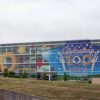 multistory modern building with wall of windows with stars and children painted on them