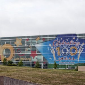 multistory modern building with wall of windows with stars and children painted on them