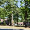 Two and three-story brick buildings with rows of windows surrounded by trees and street