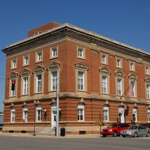 Multistory brick building on street corner with traffic passing by