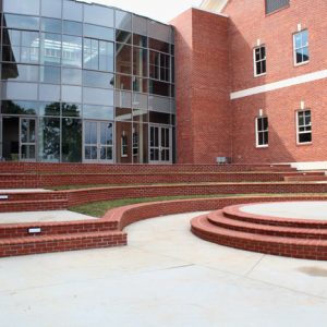 Multistory brick building with rounded glass entrance and steps