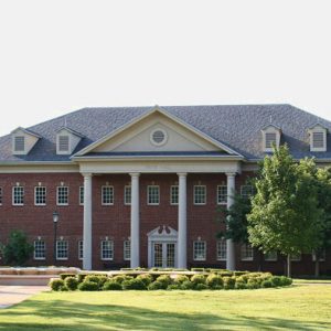 Two-story brick building with four columns and grounds