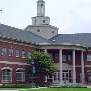 Two-story building with tower and rounded entrance with four columns