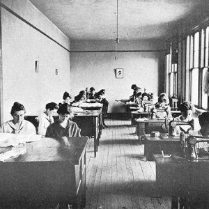 Young white women in classroom learning to sew