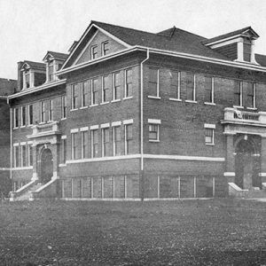 Four-story brick building with steps and arched entrances on college campus