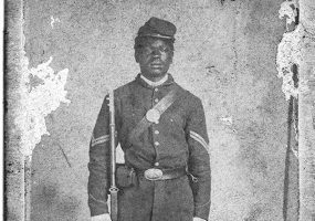 African-American man in military dress holding rifle