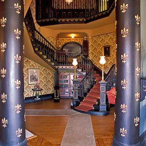 Spiral staircase beyond two painted columns with fleur-de-lis on them