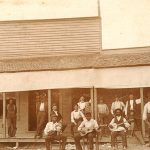 African-American musicians with their instruments and mixed group of patrons outside storefront building