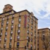 Multistory hotel building with cupola and red sign with white lettering hanging on corner facing street