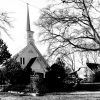 Church building with steeple and covered entrance inside iron fence