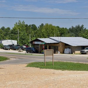 Single-story store on street with gravel parking lot