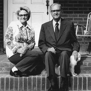 Older white woman and man with glasses sitting on brick steps