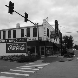 Two-story drug store on street corner with signs and traffic lights