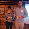 White woman with glasses smiling in striped shirt with award standing next to white man with glasses holding award