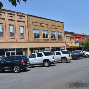 Multistory store fronts with signs and parked cars on street