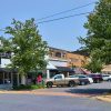 Multistory brick storefronts with parked cars and street lamp with banner in the foreground