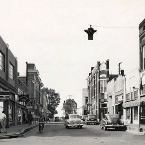 Multistory buildings with people on sidewalk and traffic light hanging above street