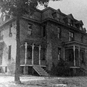 Multistory dormitory building with covered porches and trees in front yard