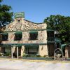 stone two story building with green trim "Arkansas House" featuring the shape of Arkansas rendered in stone