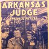 White men in suits and women in dresses with crowd behind them and "Arkansas Judge" text on faded paper