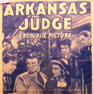 White men in suits and women in dresses with crowd behind them and "Arkansas Judge" text on faded paper