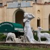 Fountain with statue of woman and deer outside multistory hotel with green awning over the entrance