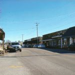 Street with brick and stone storefront buildings and parked cars