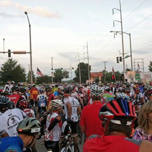 Crowd of people on bicycles with helmets on city street