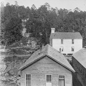 wood-frame buildings with tall windows on tree-covered hill side