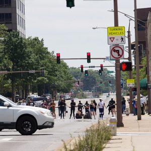 Mixed group of people standing in busy city street with tall multistory buildings around them