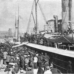 Crowd of people gathered on boat dock with two ships