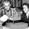 White man and woman watching a rabbit play a tiny piano