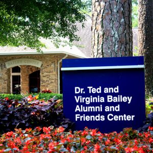 Building with blue sign "Dr. Ted and Virginia Bailey Alumni and Friends Center"