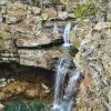 Natural waterfall over rock face leading to a pool below