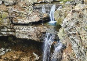 Natural waterfall over rock face leading to a pool below