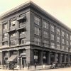 Four-story building on street corner with people and cars