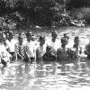 White men women and children standing in river