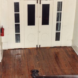 Doors with decorative windows and chandelier above them as seen from staircase