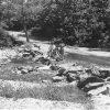 White man and women standing on dirt road by creek