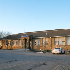 one story stone building with parking lot in front